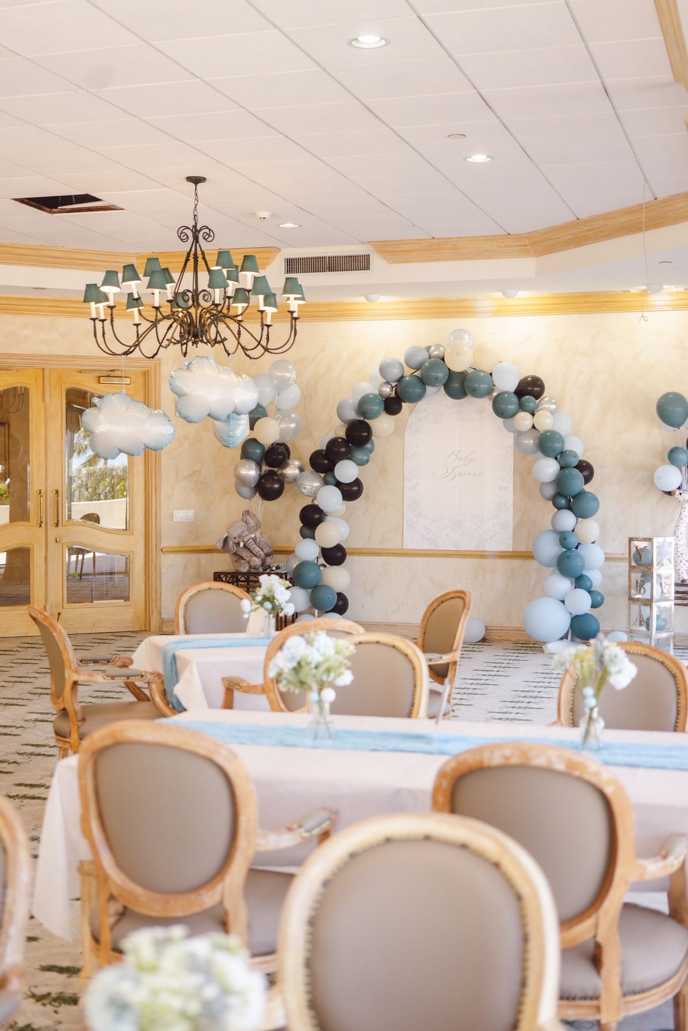 Gender reveal styled with soft blue balloon arch and chandelier